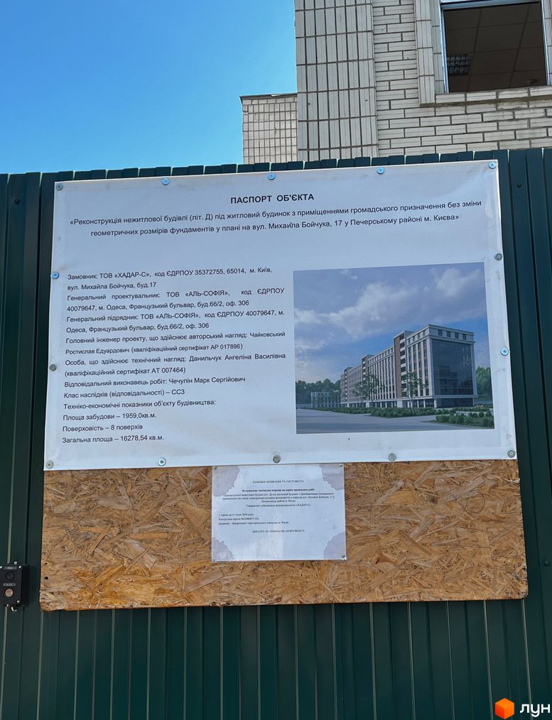 Реконструкція нежитлової будівлі під житловий будинок з приміщеннями громадського призначення на вул. Михайла Бойчука, 17. Фасад будівлі з вікнами та прибудинкова територія з деревами.