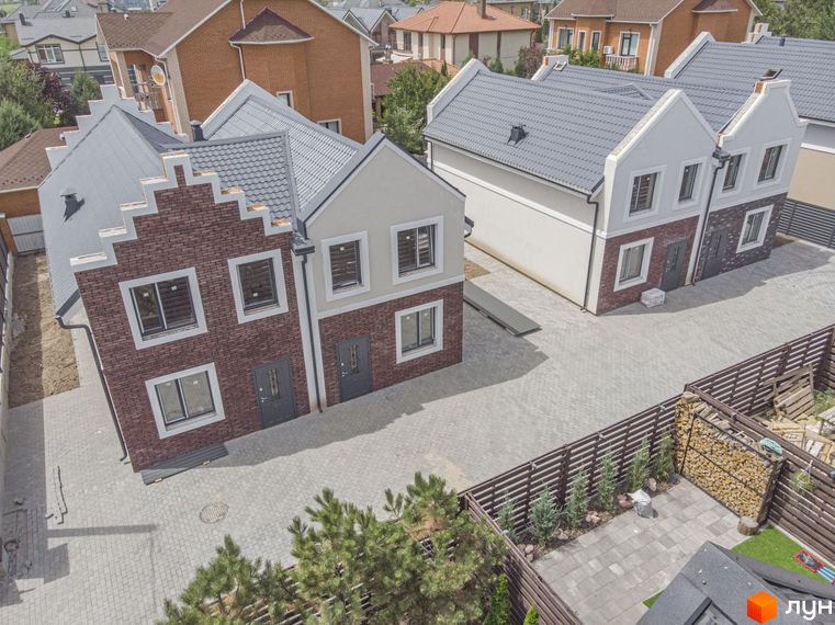 Дуплекси Lucky Home – двоповерхові будинки з цегляним фасадом та сірим дахом, розташовані на брукованій прибудинковій території з парканом та зеленими насадженнями.
