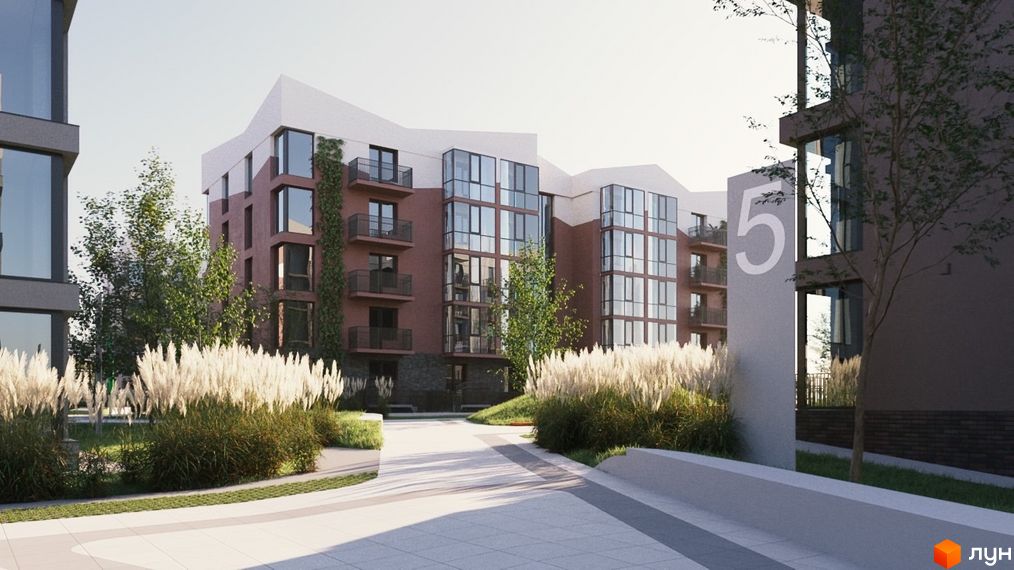 Зовнішній вигляд житлового комплексу Гордість з цегляними фасадами, великими вікнами та балконами. Прибудинкова територія озеленена високою травою та деревами.