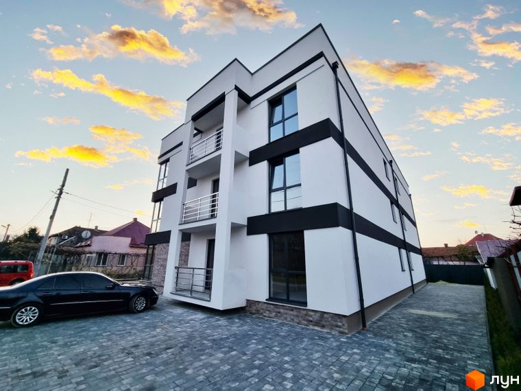 Зображення фасаду та прибудинкової території Житлового комплексу Преміум Хаус. Багатоповерховий будинок з балконами та автомобілем на подвір'ї.