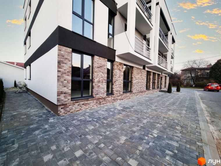 Зовнішній вигляд Житлового комплексу Преміум Хаус з оздобленням фасаду цеглою. На передньому плані викладена бруківкою прибудинкова територія.