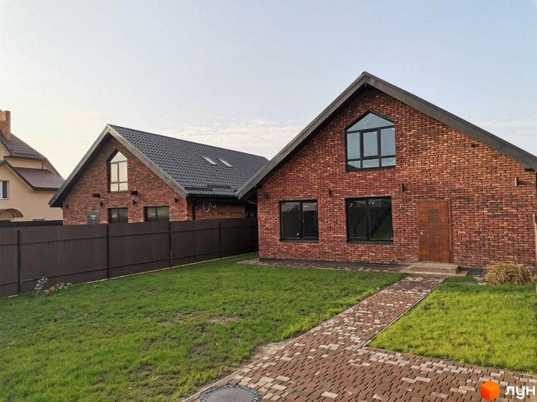 Котеджне містечко Одноповерховий Київ - Дніпро: цегляні будинки з темними дахами та вікнами. Перед ними зелений газон і брукована доріжка.