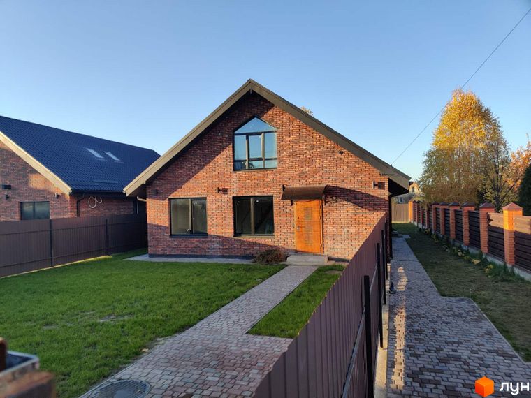 Котеджне містечко Одноповерховий Київ - Дніпро. Цегляний будинок з великими вікнами та дерев'яними дверима, огороджений парканом, з доглянутим газоном та бруківкою.