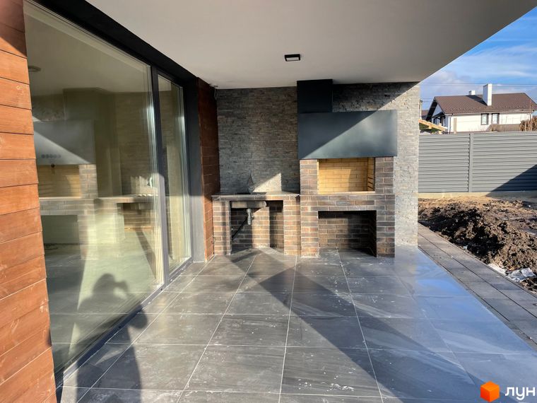 Зовнішній вигляд будинку новобудови на вул. Мазепи: тераса з великими скляними дверима та вбудованою зоною барбекю.