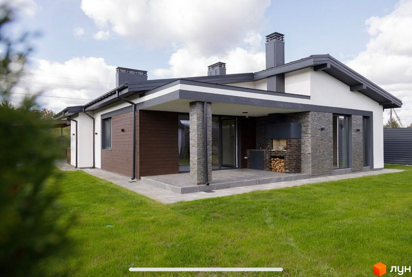 Сучасний одноповерховий будинок з коричневою та сірою обробкою, великими вікнами та відкритою терасою з каміном. Прибудинкова територія з доглянутим газоном.