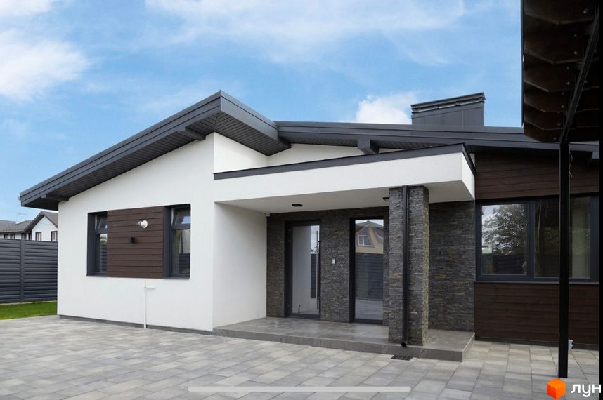 Сучасний житловий комплекс на вул. Мазепи. Зовнішній вигляд будинку з білою штукатуркою, темним дахом та дерев'яними елементами, вимощена плитка на прибудинковій території.