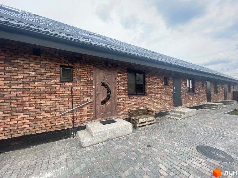 Котеджне містечко КМ Одноповерховий Київ - Віта-Поштова. Фасад будинку з червоної цегли, вхідні двері з візерунком, вимощені бруківкою двір.