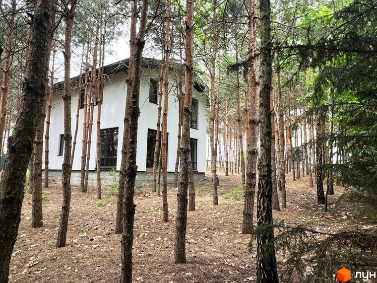 Вигляд двоповерхового будинку з великими вікнами в Котеджному містечку GREEN CLUB, оточеного сосновим лісом.