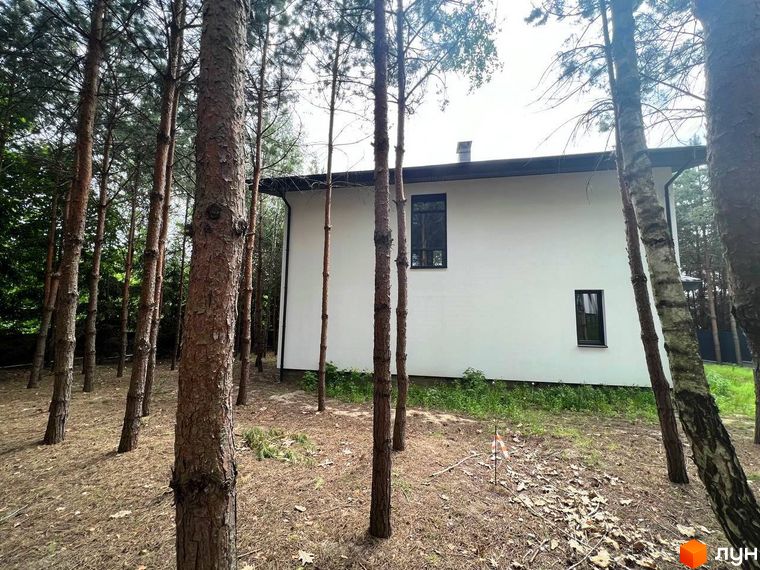 Вигляд будинку в Котеджному містечку GREEN CLUB з великими вікнами та темним дахом. Навколо будинку ростуть сосни.