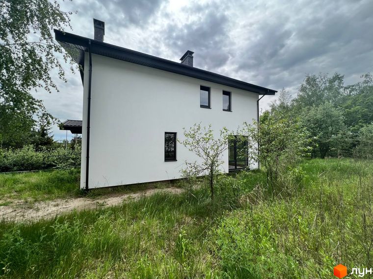 Зовнішній вигляд будинку в Котеджному містечку GREEN CLUB. Навколо будинку зелена трава та дерева.