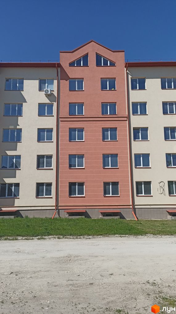 Зовнішній вигляд будинку на вулиці Січинського. Багатоповерхова будівля з вікнами та зеленим газоном перед нею.