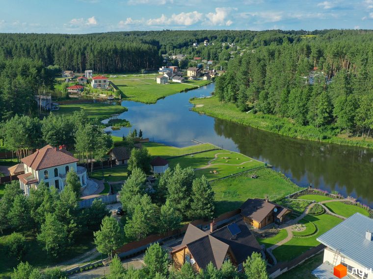 Котеджне містечко КМ Swisstown: розкішні будинки з червоними дахами біля озера та лісу. Прибудинкова територія з доглянутими газонами та доріжками.