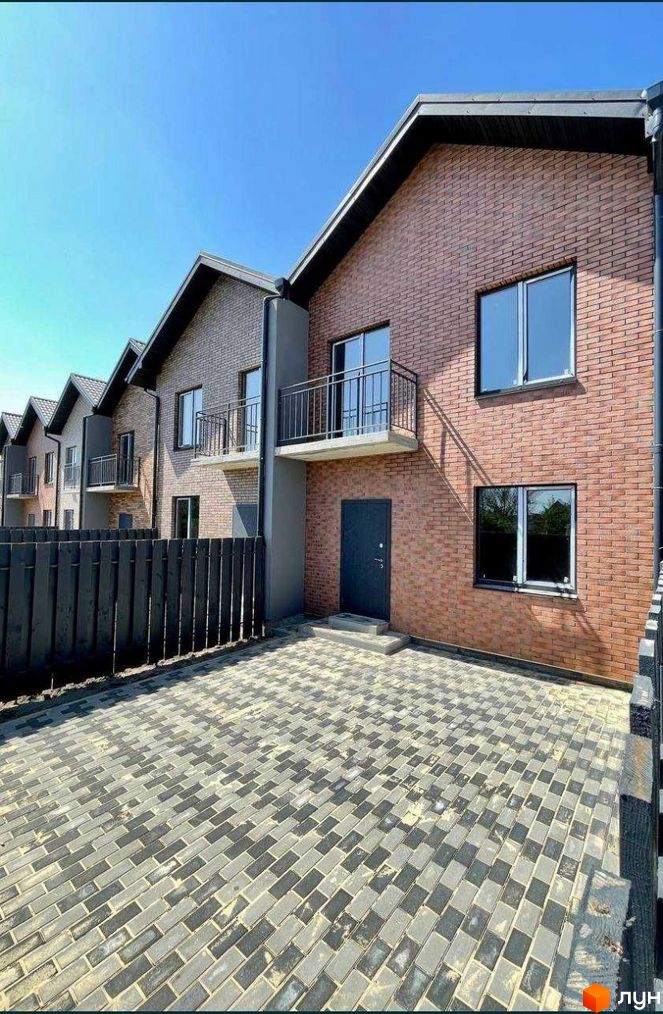 Зовнішній вигляд таунхаусів Чемпіон з цегляним фасадом та балконами. Прибудинкова територія з бруківки та дерев'яного паркану.