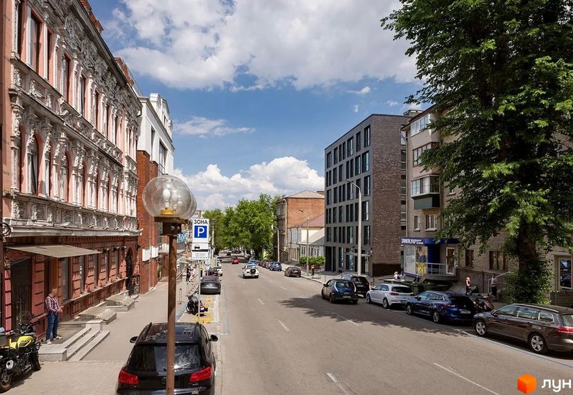 Житловий комплекс ArtHof – це багатоповерхова будівля з темним фасадом та численними вікнами, розташована на міській вулиці з припаркованими автомобілями та деревами.