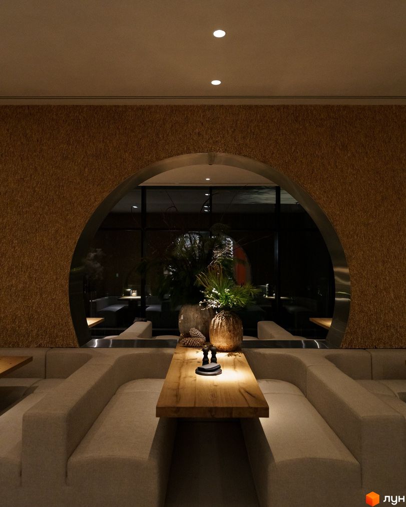 Інтер'єр апарт-комплексу Mountain Residence з диванами та столом. Дизайн інтер'єру з аркою та рослинами.