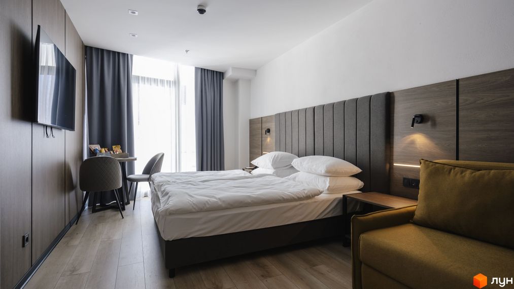 Апарт-комплекс Mountain Residence: затишна спальня з двоспальним ліжком, телевізором та зоною відпочинку біля вікна. Сучасний дизайн інтер'єру для комфортного проживання.