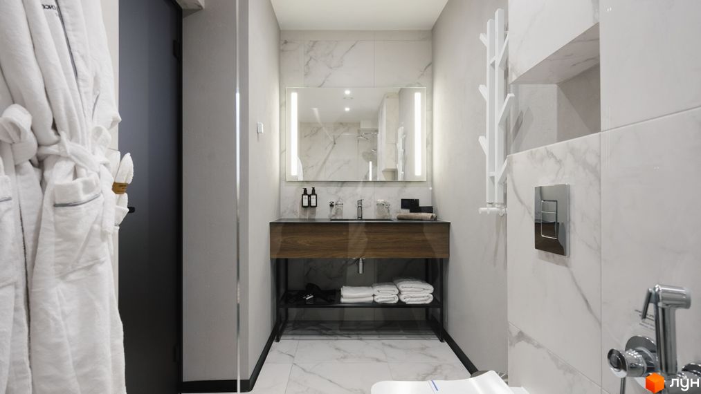 Ванна кімната в апарт-комплексі Mountain Residence з білими халатами, мармуровою плиткою та дерев'яною тумбою під умивальник.