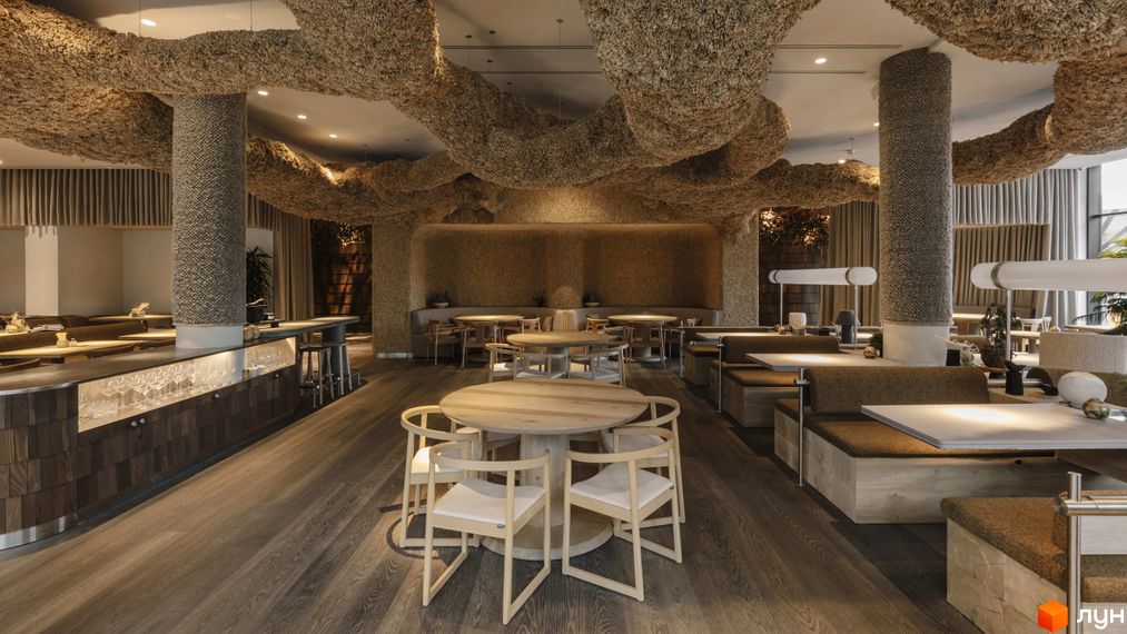 Інтер'єр ресторану з дерев'яними столами та стільцями, оздобленням з натуральних матеріалів та незвичайними стельовими конструкціями.