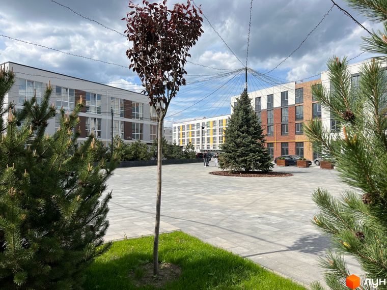 Зображення сторінки ЖК Sanville Park. На фото видно будівлі з великими вікнами та доглянуту прибудинкову територію з деревами.