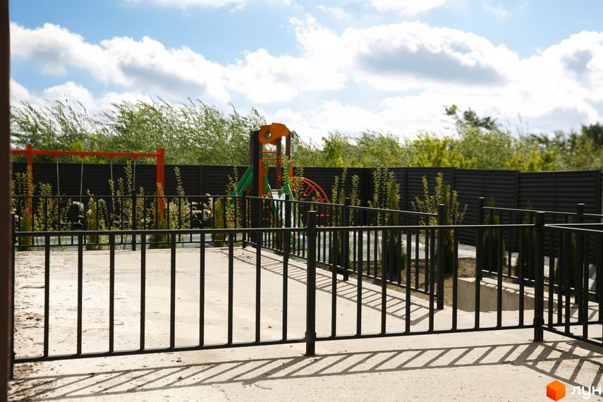 Фото дитячого майданчика в Житловому комплексі клубного типу Обрій. На задньому плані зелені насадження та огорожа.