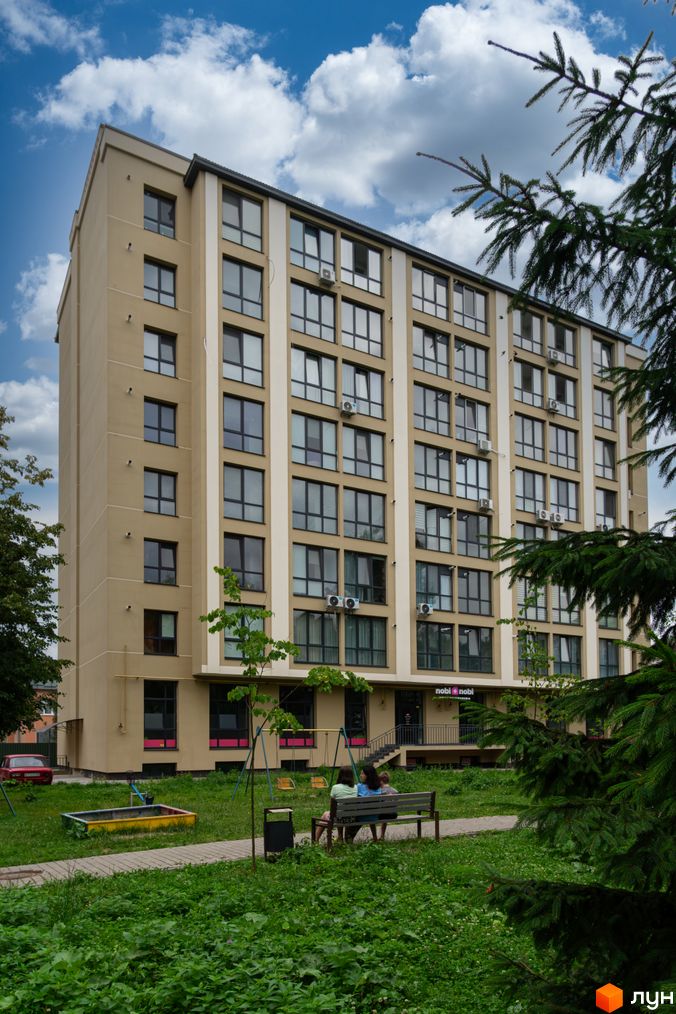 Будинок житлового комплексу на вулиці Короля Данила, 11, з великою кількістю вікон та кондиціонерів. Поруч розташований дитячий майданчик та зелена зона.