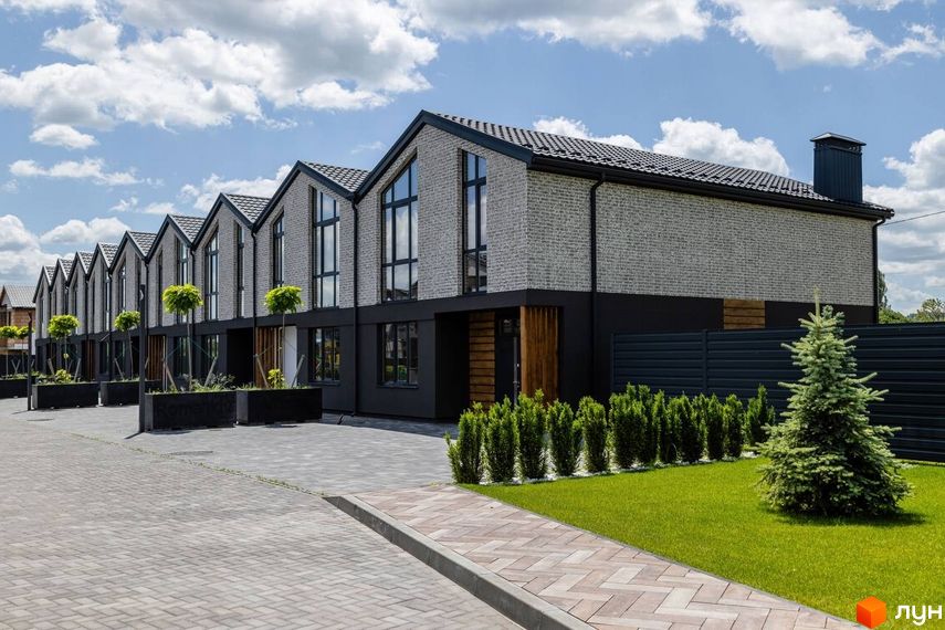 Котеджне містечко Romankiv Village: фасади будинків з сірої цегли та чорної штукатурки, великі вікна, зелені насадження та вимощена територія.