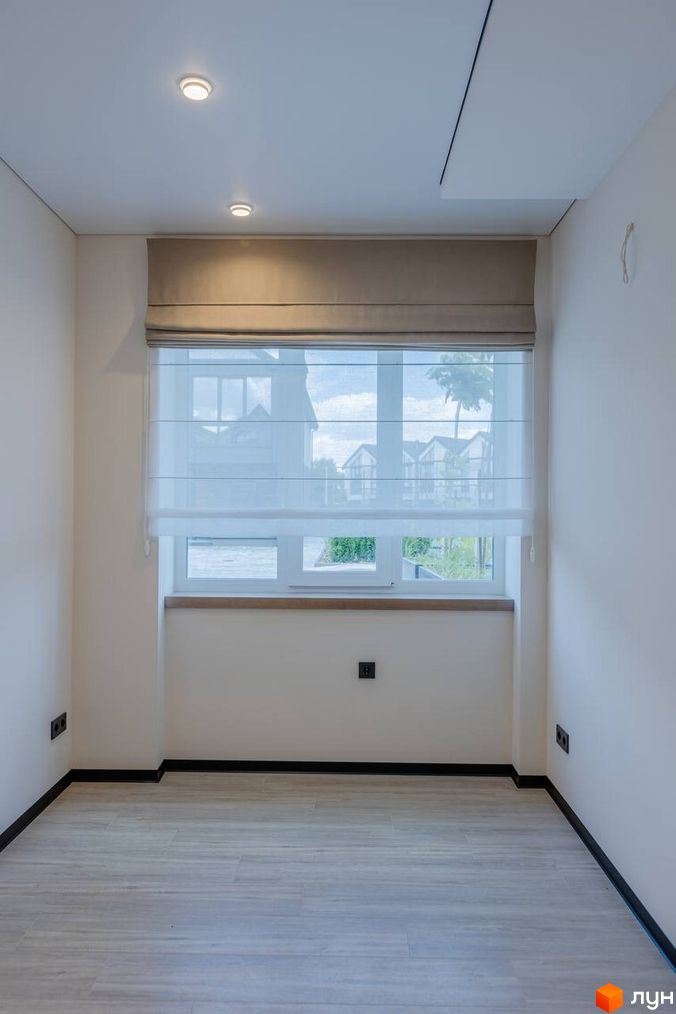 Інтер'єр кімнати з панорамним вікном та римськими шторами в котеджному містечку КМ Romankiv Village. Світлі стіни та підлога створюють затишну атмосферу.