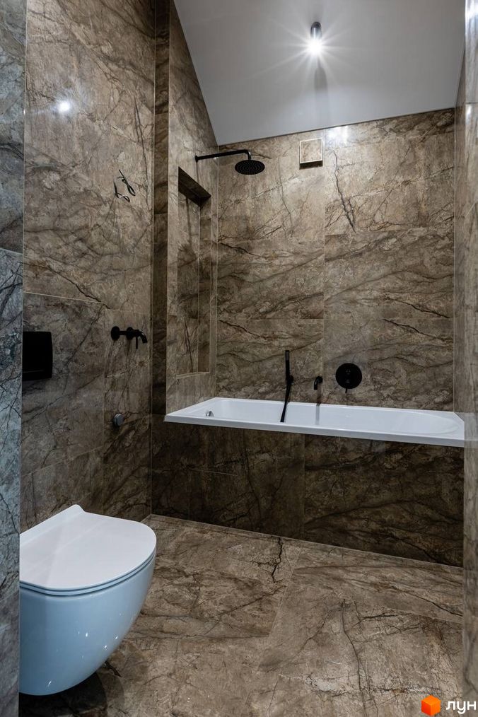 Сучасний дизайн ванної кімнати з мармуровим оздобленням у ЖК Romankiv Village. Ванна кімната оснащена душем, ванною та туалетом.