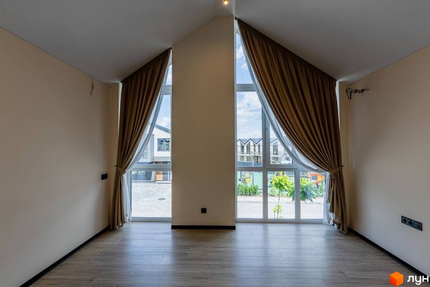 Котеджне містечко Romankiv Village. Великі панорамні вікна з коричневими шторами відкривають вид на двір з дитячим майданчиком та сусідні будинки.