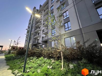 Житловий комплекс Park Residence з фасадом сірого та бежевого кольору, балконами та озелененою прибудинковою територією з деревами та кущами.