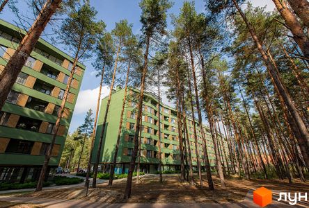 Зелений багатоповерховий будинок ЖК Park Town серед високих дерев. На території комплексу є доріжки та зелені насадження.